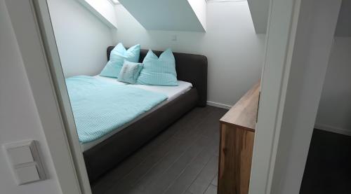 a small bedroom with a bed with blue pillows at Ferienwohnung Spreewald in Schlepzig