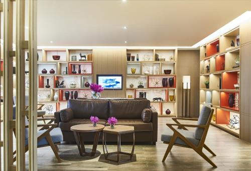 a living room with a couch and tables and shelves at Amari Bangkok in Bangkok