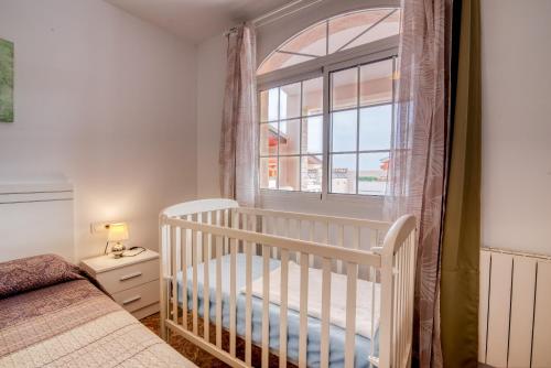 a white crib in a bedroom with a window at Chalet Bonavista in Benifayó