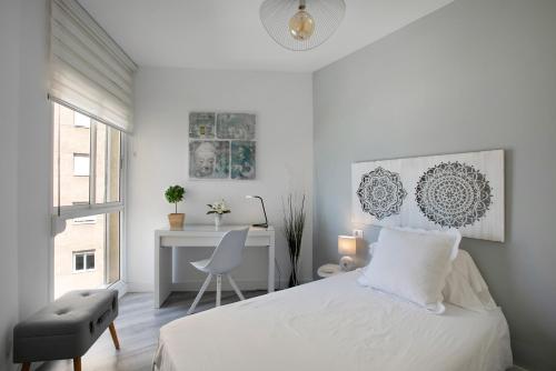 a white bedroom with a bed and a desk at Mi casa de Radazul in El Rosario
