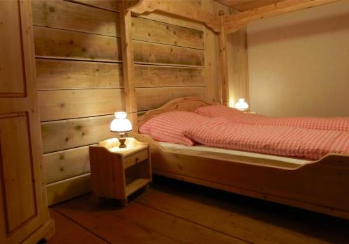 a bedroom with two beds with wooden walls and lamps at Schwarzwaldbauernhaus Bernau in Bernau im Schwarzwald