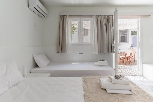 a white room with two beds and a window at A Tinian Room 5 in Tinos