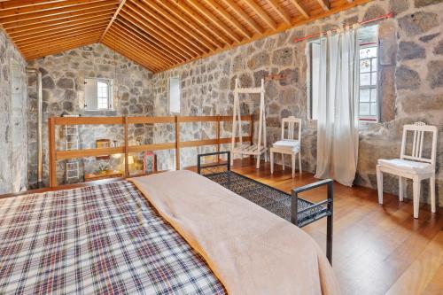 a bedroom with a bed in a room with stone walls at Serreta Island Home in Serreta