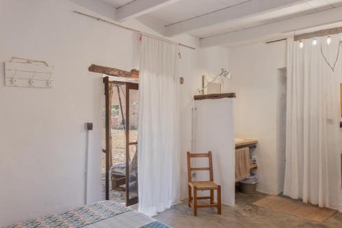 a bedroom with white walls and a bed and a chair at Can Vicent in Illes Balears