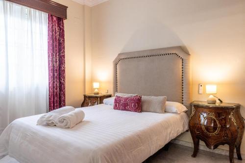 a bedroom with a bed with white sheets and pink pillows at Villa Candelaria Sol y Piscina in Bormujos