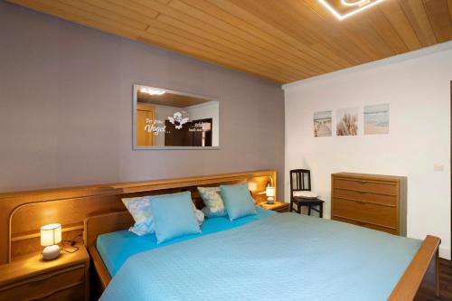 a bedroom with a blue bed with a wooden headboard at Ferienwohnung Kühlmeyer in Bundenthal