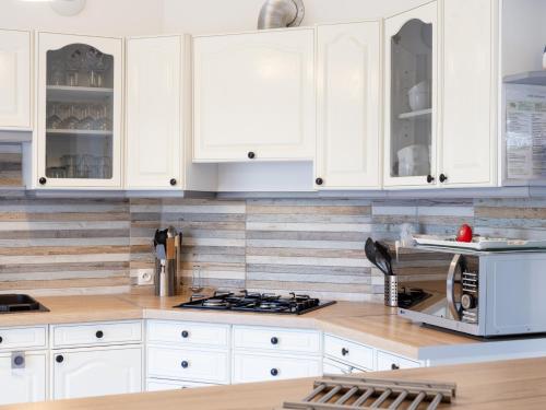 a kitchen with white cabinets and a stove top oven at L'escale Kénanaise in Saint-Quay-Perros