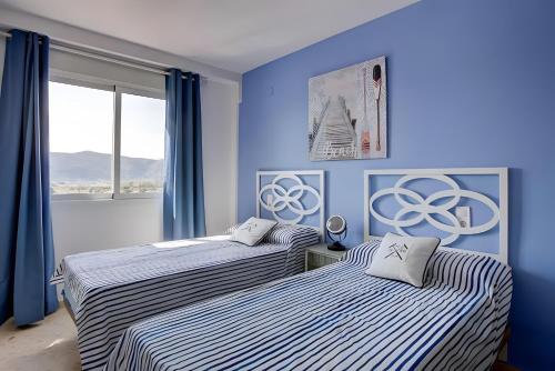two beds in a room with blue walls at Atico Playa Gandia in Playa de Gandia