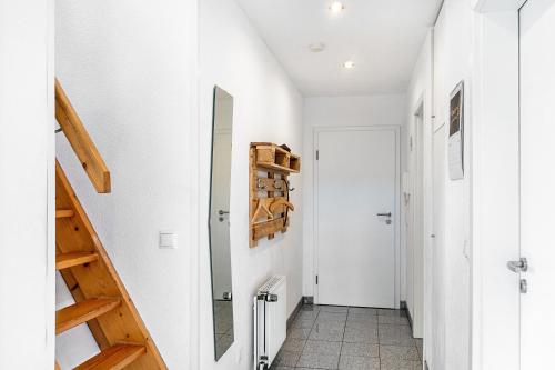 a hallway with white walls and wooden stairs at Meeresfeeling in Horumersiel in Horumersiel
