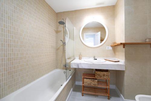 a bathroom with a sink and a tub and a mirror at Terrazas de doñana b91a in Sanlúcar de Barrameda