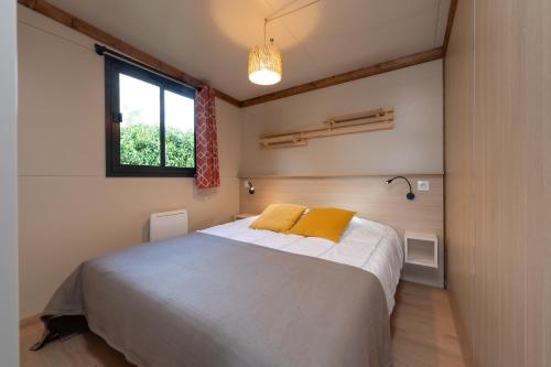 a bedroom with a large bed with a window at Chalet 35m2 - Molène in Plouhinec