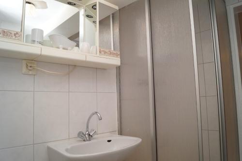 a white bathroom with a sink and a mirror at Alte Schule in Bad Wildungen