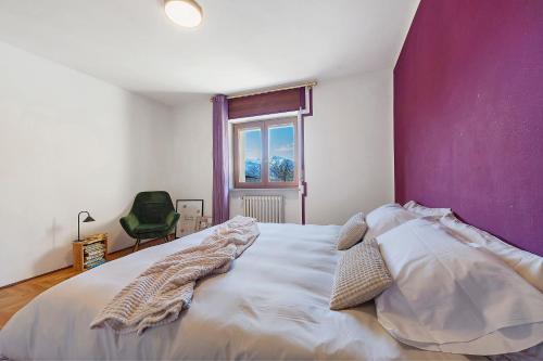 a bedroom with a large white bed with a purple wall at Alpenglow Maison Lugon in Saint-Christophe