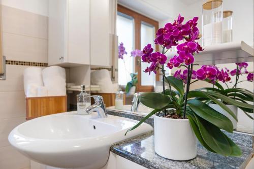 a bathroom with a sink and a vase with purple flowers at Alpenglow Maison Lugon in Saint-Christophe
