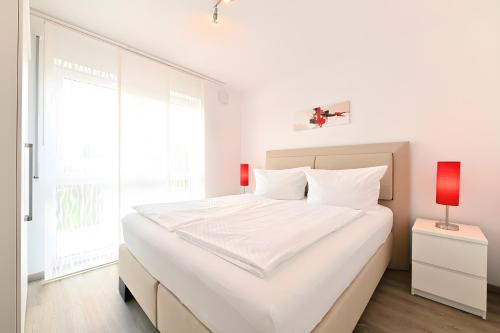 a white bedroom with a large white bed and a red lamp at Dinkelbach Traumblick 3 C in Hengnau