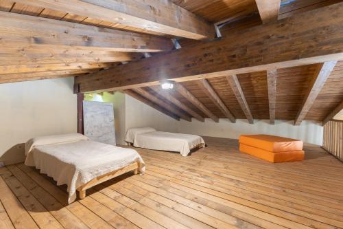 two beds in a room with wooden floors and wooden ceilings at La Morada De Piedralaves in Piedralaves