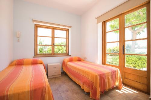 two beds in a room with two windows at Villa Republica Argentina in Ciutadella