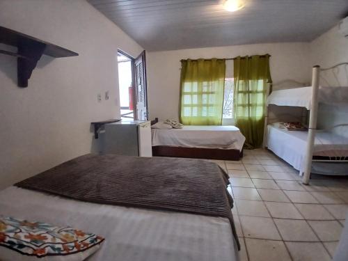 a small room with two beds and a window at Roses hostel e pousada in Pipa