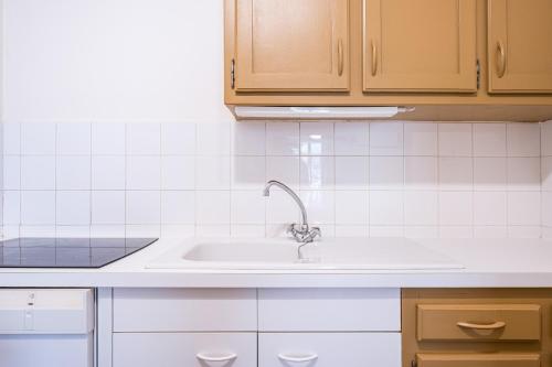 a kitchen with a sink and white tiles at Lauziere centre 6 couchages in Saint-François-Longchamp