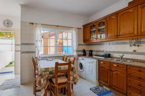 a kitchen with a table and a washing machine at Alojamento Local Família Coelho in Quinta do Conde