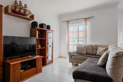 a living room with a couch and a flat screen tv at Alojamento Local Família Coelho in Quinta do Conde