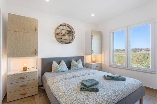 a bedroom with a bed with two towels on it at Drop In Beach Apartments in Lourinhã