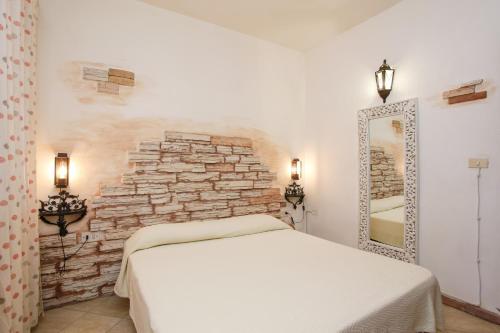 a bedroom with a white bed and a stone wall at mirtagru casa dell'olivastro in Agrustos