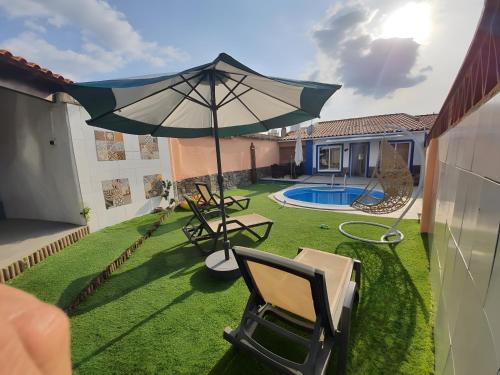 a patio with an umbrella and chairs and a pool at Cantinho de Paz in São Marcos do Campo