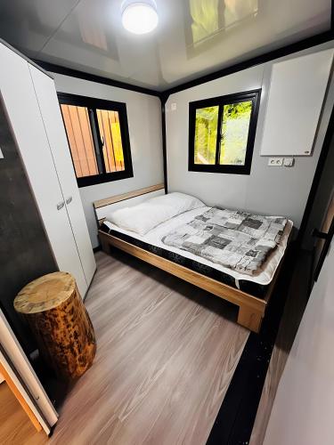 a small bedroom with a bed and two windows at Tinyhaus 200 in Zadelsdorf