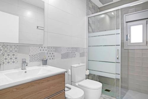 a white bathroom with a toilet and a sink at Villa Adán con Piscina Majestuosa in Cádiz