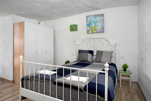 a bedroom with a white bed with a blue blanket at Ca' Navarro in Vega de San Mateo