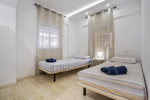 two beds in a room with white walls and wooden floors at Las Américas Seafront - Free Wi-fi in Playa de las Americas