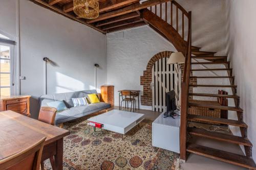 a living room with a couch and a spiral staircase at La maison blanche in Nazelles
