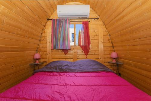 a bedroom with a pink bed in a wooden cabin at Pink Pod in Saint-André