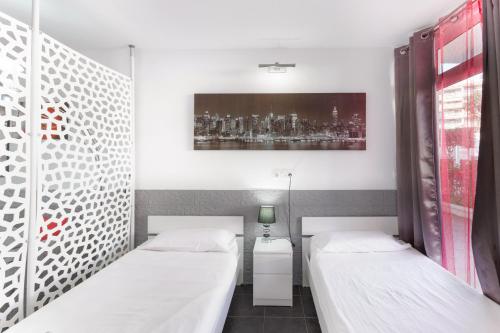 a room with two beds and a painting on the wall at Estudio Yumbo Playa Del Ingles in San Bartolomé