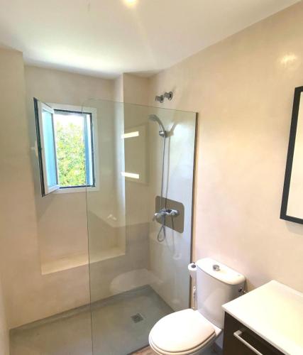 a bathroom with a toilet and a glass shower at Villa los Tres Menorca in Cala en Bosc
