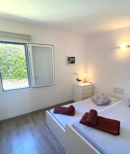 a white bedroom with two beds and a window at Villa los Tres Menorca in Cala en Bosc
