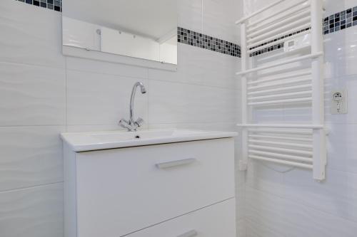a white bathroom with a sink and white cabinets at Gite du maine in Langon