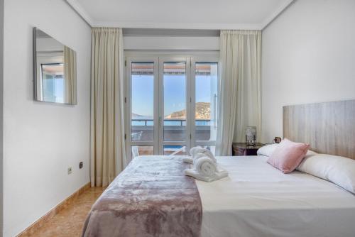 a bedroom with a large white bed with a window at Calpe Vistas y Playa in Calpe