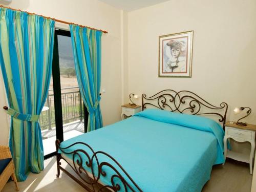 a bedroom with a blue bed and a balcony at Sami Beach Villas Nefeli in Karavomylos