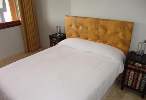 a bedroom with a white bed with a wooden headboard at Villa Bea ii in San Bartolomé