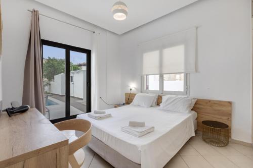 a white bedroom with a bed and a window at Luxsuites in Chania