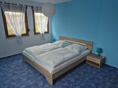 a blue bedroom with a bed and two windows at Ferienwohnung Rochlitzer Berg Blick in Seelitz