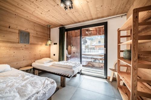 two beds in a room with wooden walls at Martonne - haut Roca immobilier in Châtel