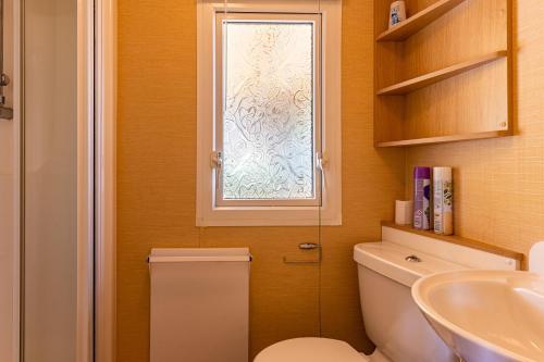 a bathroom with a toilet and a window at Mobilehome au bord de l'eau in Gastes