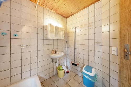 a white tiled bathroom with a sink and a toilet at Bungalow 4 - Kimbucht in Reichendorf
