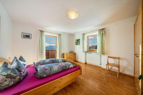 a bedroom with a bed and a chair in it at Stücklhof Wohnung Rose in San Genesio Atesino