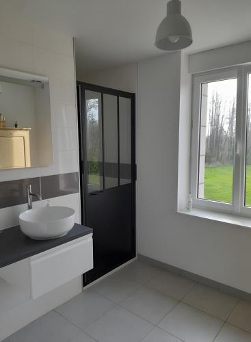a white bathroom with a sink and a window at La Grange Aux Oiseaux in Beaulieu