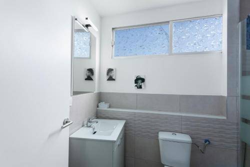 a bathroom with a toilet and a sink and a window at Villa Monica in Agüimes