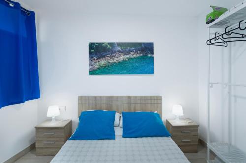 a bedroom with a bed with blue sheets and two night stands at Villa Monica in Agüimes